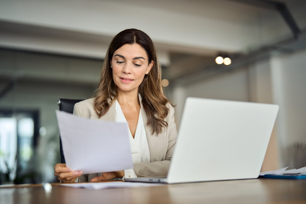 woman reading paper sitting at desk.